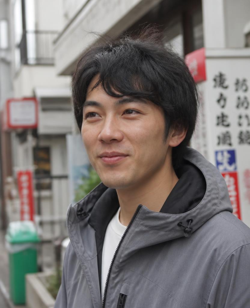 Portrait of a smiling man with cherry blossom trees behind him